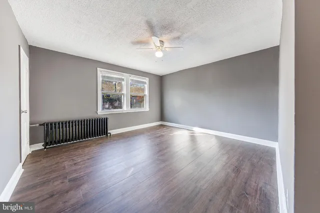 an empty room with wooden floor chandelier and windows