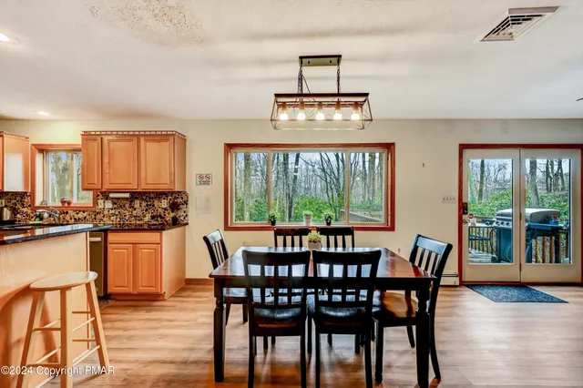 a kitchen with granite countertop a stove a sink a dining table and chairs with wooden floor