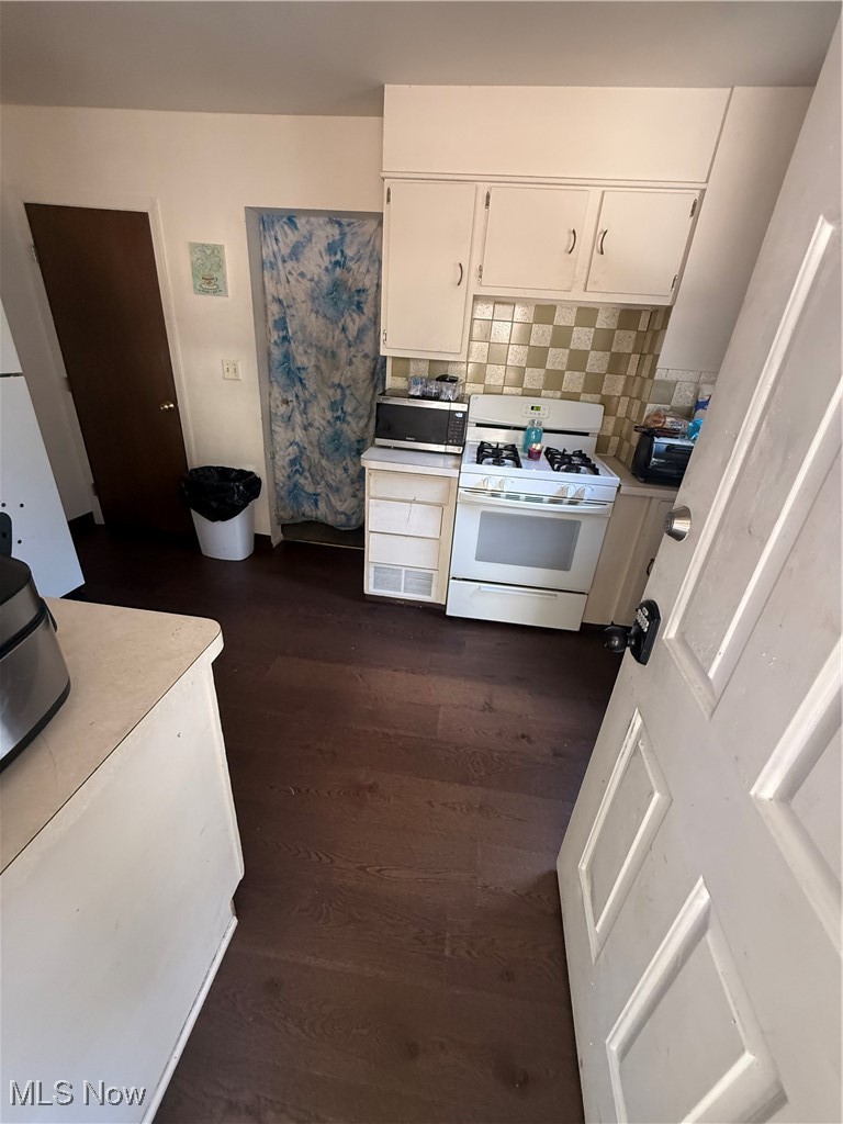 746 Wooster Road North Barberton, OH 44203 - Photo 25 of 44 Kitchen featuring backsplash, light countertops, white cabinetry, range, and dark wood-type flooring