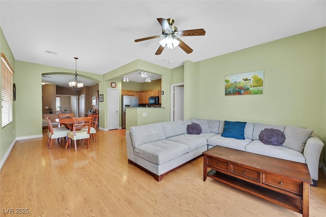10983 Pumpkin Ridge Avenue Las Vegas, NV 89135 - Photo 13 of 35 Living area with arched walkways, baseboards, light wood finished floors, and ceiling fan with notable chandelier