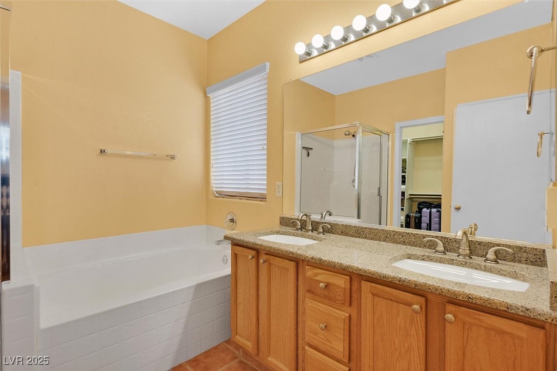10983 Pumpkin Ridge Avenue Las Vegas, NV 89135 - Photo 17 of 35 Bathroom featuring double vanity, a garden tub, a shower stall, and a sink