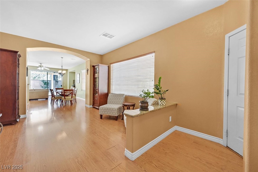 10983 Pumpkin Ridge Avenue Las Vegas, NV 89135 - Photo 3 of 35 Sitting room featuring arched walkways, a notable chandelier, visible vents, light wood-style flooring, and baseboards