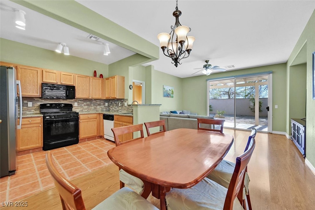 10983 Pumpkin Ridge Avenue Las Vegas, NV 89135 - Photo 7 of 35 Dining room with light wood-style floors, baseboards, visible vents, and ceiling fan with notable chandelier