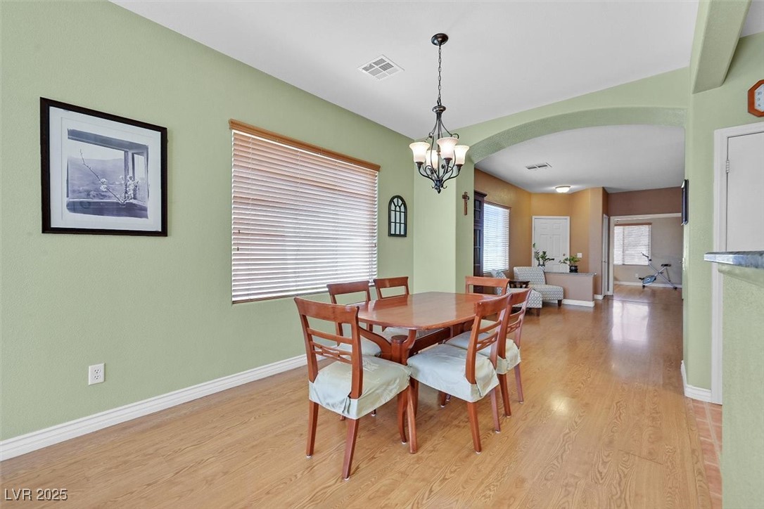 10983 Pumpkin Ridge Avenue Las Vegas, NV 89135 - Photo 10 of 35 Dining room with baseboards, visible vents, arched walkways, light wood-type flooring, and a notable chandelier