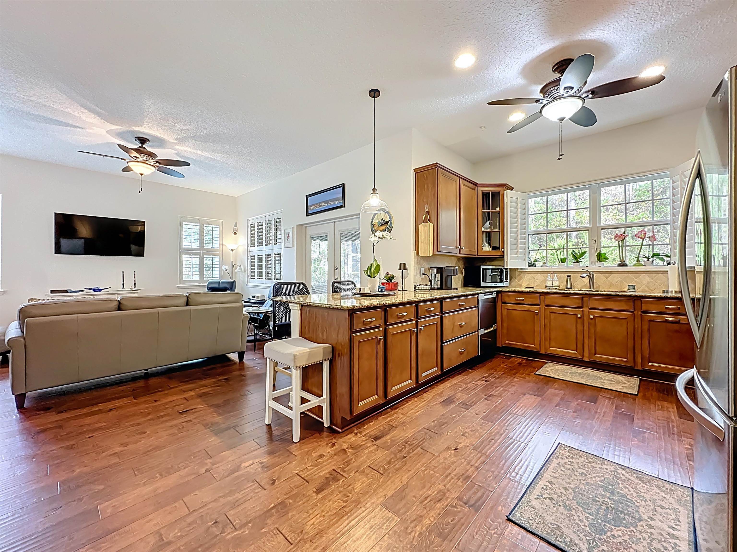 130 Grand Ravine Drive St. Augustine, FL 32086 - Photo 41 of 42 Kitchen featuring ceiling fan, brown cabinets, a textured ceiling, light stone countertops, and open floor plan