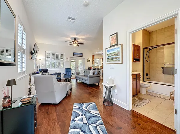 a living room with furniture a ceiling fan a window and a flat screen tv