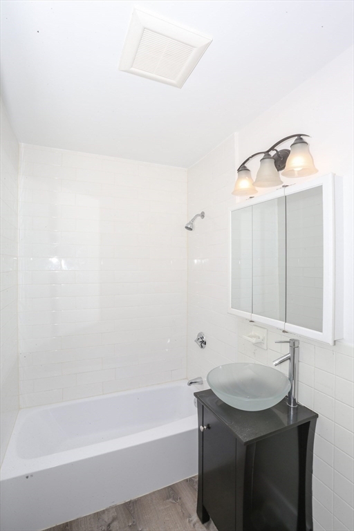 461 Washington Street, Unit 301 Boston, MA 02135 - Photo 2 of 13 a bathroom with a sink a bathtub and a mirror