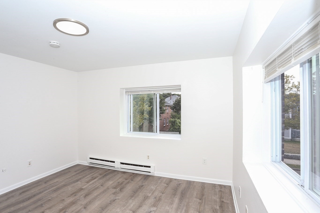 461 Washington Street, Unit 301 Boston, MA 02135 - Photo 8 of 13 an empty room with wooden floor and windows