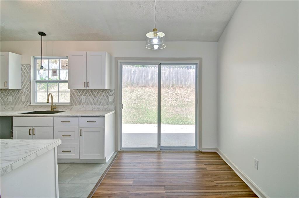 2665 Ivydale Court Southwest Atlanta, GA 30311 - Photo 14 of 45 a kitchen with granite countertop a stove a sink and white cabinets with wooden floor