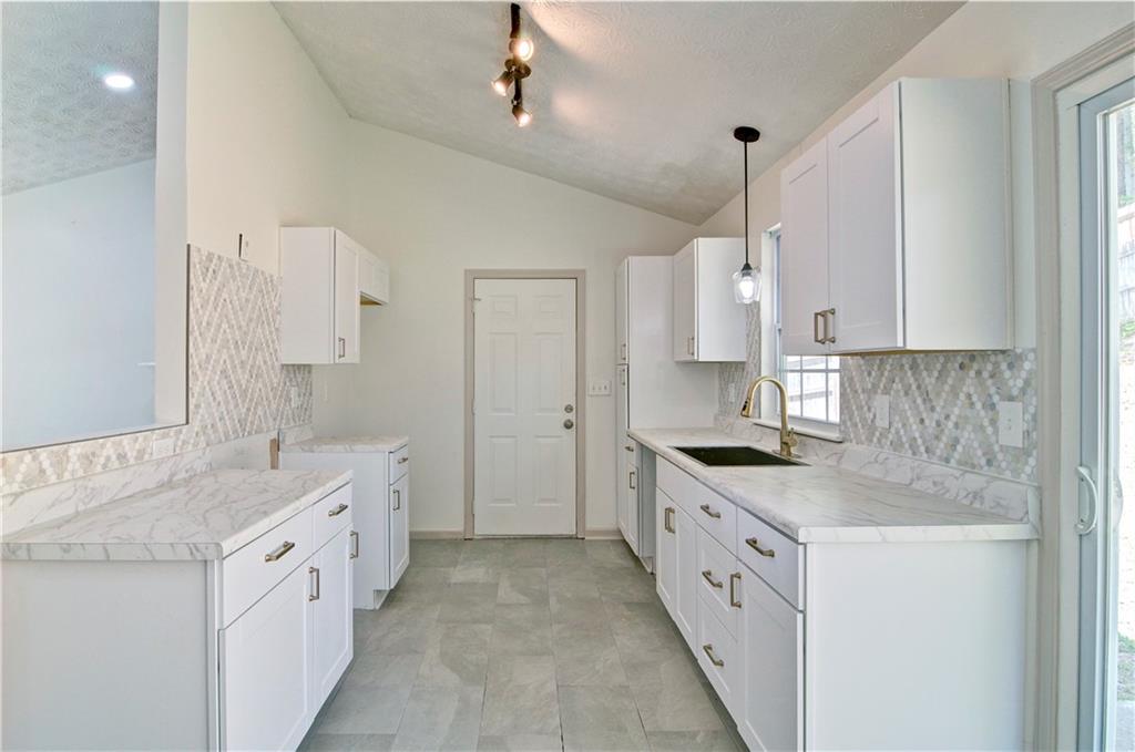 2665 Ivydale Court Southwest Atlanta, GA 30311 - Photo 18 of 45 a large white kitchen with a granite countertop sink and a stove