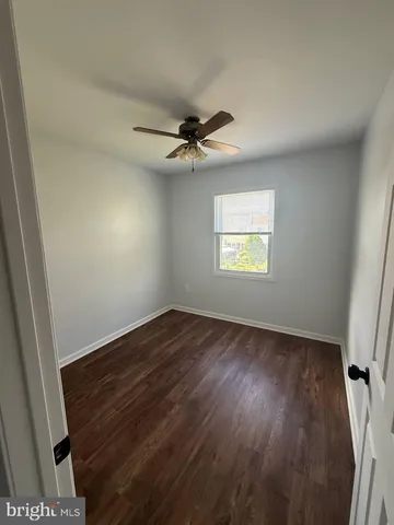an empty room with wooden floor ceiling fan and windows