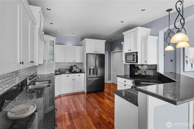a kitchen with a refrigerator a stove and white cabinets with wooden floor