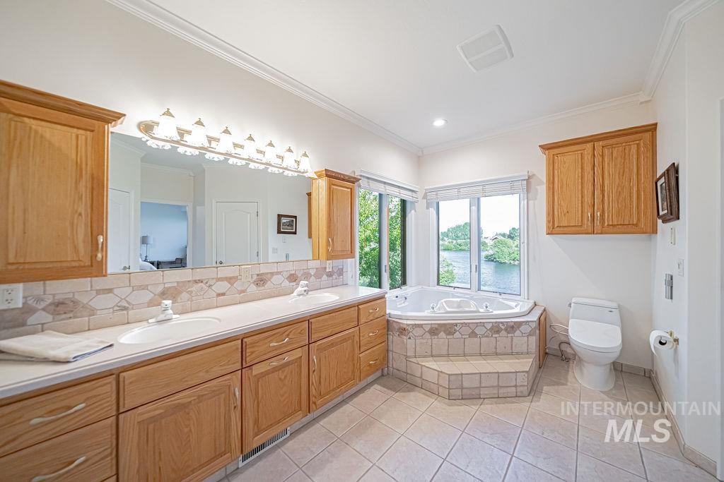 2700 North River Road St. Anthony, ID 83445 - Photo 22 of 50 Bathroom features a corner jetted tub with panoramic river views, making every soak a serene experience. An additional ceiling heater ensures warmth and comfort, enhancing the spa atmosphere.