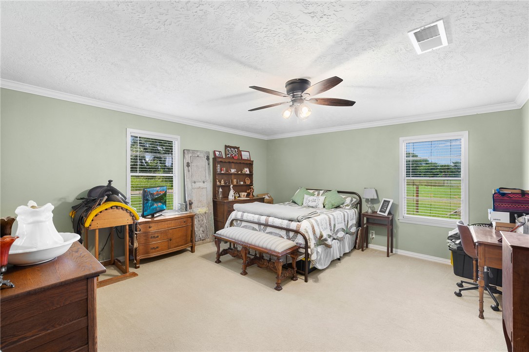 4450 Greenbriar Road Madisonville, TX 77864 - Photo 12 of 27 a spacious bedroom with a bed and a chandelier