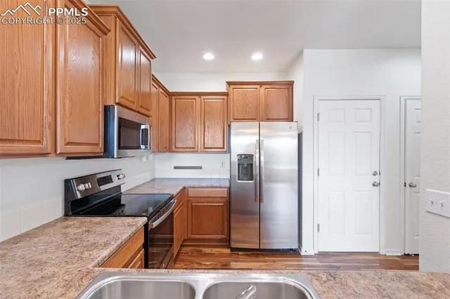 a kitchen with stainless steel appliances granite countertop a refrigerator a stove and a sink