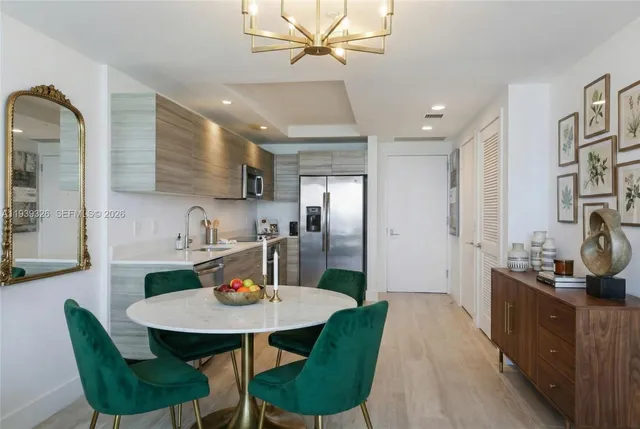 a kitchen with stainless steel appliances kitchen island granite countertop a dining table chairs and a refrigerator