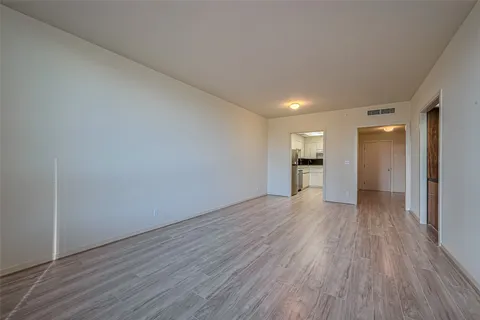 a view of a big room with wooden floor and a kitchen