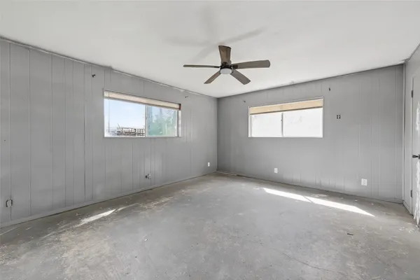 an empty room with windows and fan