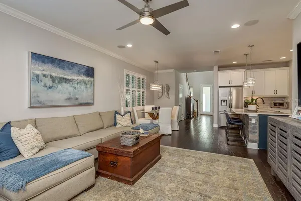 a living room with furniture kitchen view and a wooden floor
