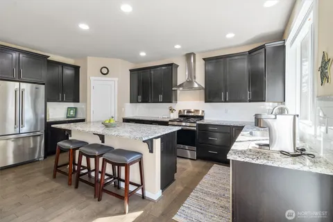 a kitchen with granite countertop a refrigerator stove top oven and sink