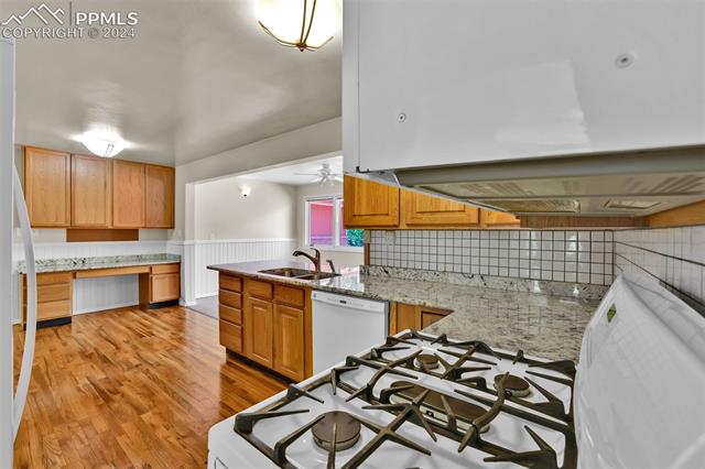 1404 West Cheyenne Road Colorado Springs, CO 80906 - Photo 23 of 50 Kitchen with light hardwood floors, sink, range hood, decorative backsplash, and white appliances