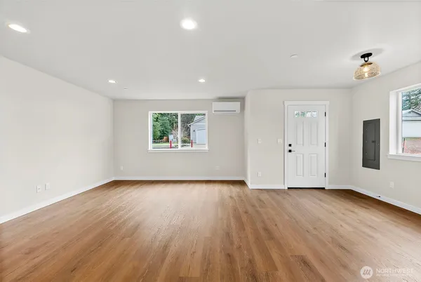 a view of an empty room with wooden floor and a window