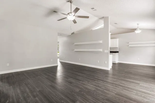 an empty room with wooden floor ceiling fan and windows