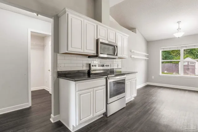 a kitchen with granite countertop white cabinets and wooden floor