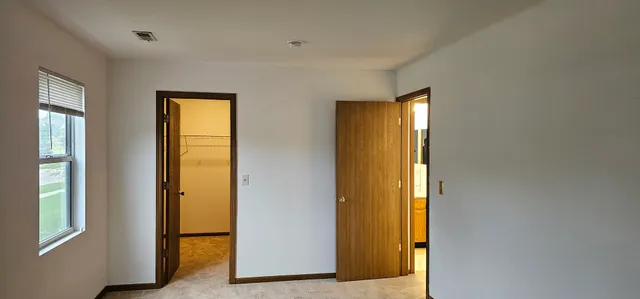 a view of an empty room with wooden floor and a bathroom