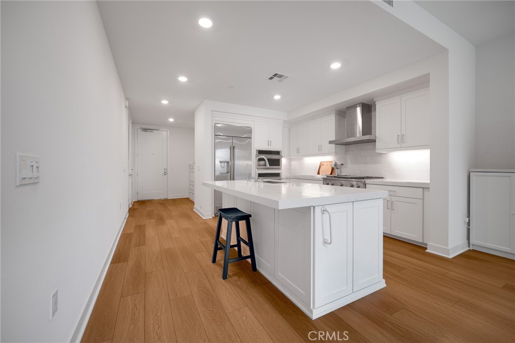 2202 Rivington Irvine, CA 92612 - Photo 5 of 21 a kitchen with stainless steel appliances granite countertop a sink a stove a refrigerator and white cabinets with wooden floor