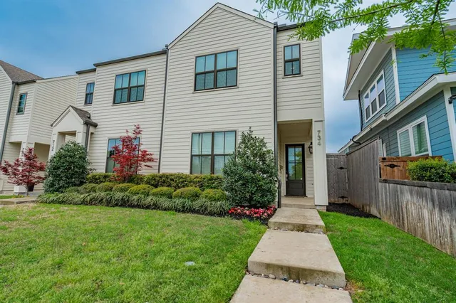 a front view of a house with a yard and potted plants