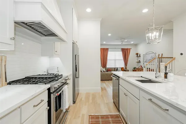 a kitchen with stainless steel appliances kitchen island granite countertop a stove a sink and white cabinets with wooden floor