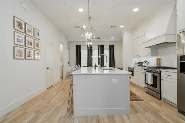 a kitchen with kitchen island stainless steel appliances a sink stove and cabinets