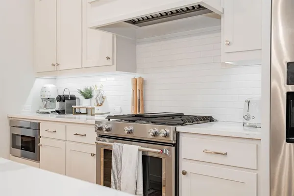 a kitchen with stainless steel appliances kitchen island a table chairs and a refrigerator