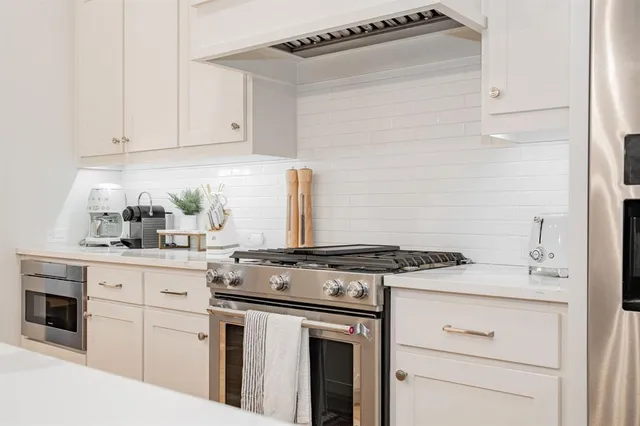 a kitchen with stainless steel appliances kitchen island a table chairs and a refrigerator