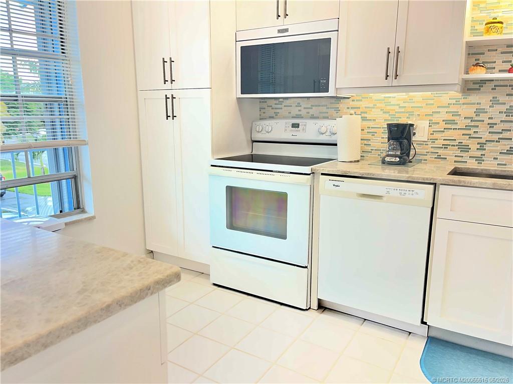 1858 Southwest Palm City Road, Unit 203 Stuart, FL 34994 - Photo 6 of 21 a kitchen with granite countertop white cabinets and white appliances