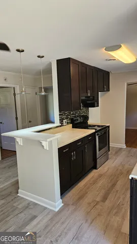 a room with kitchen island stainless steel appliances a sink a counter top space and cabinets