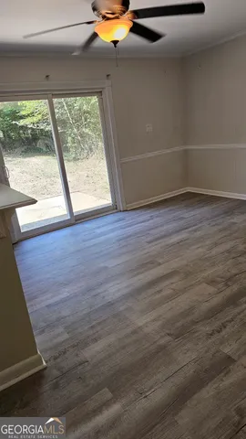 a view of an empty room with wooden floor and windows