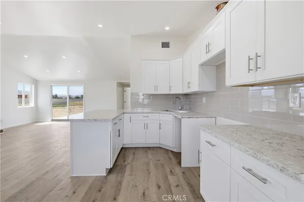 a kitchen with granite countertop white cabinets and white appliances