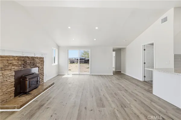 an empty room with wooden floor fireplace and windows
