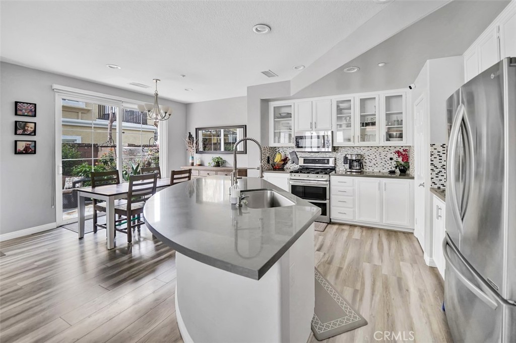 12 Geranium Irvine, CA 92618 - Photo 2 of 20 a kitchen with granite countertop a refrigerator a stove a dining table and chairs with wooden floor