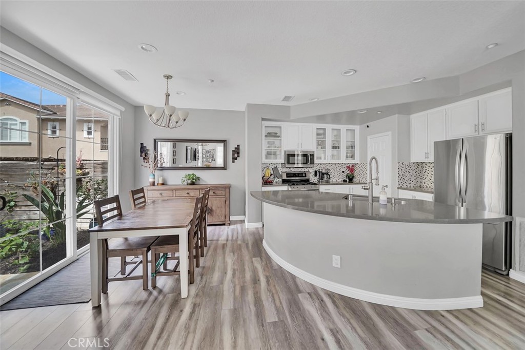 12 Geranium Irvine, CA 92618 - Photo 3 of 20 a kitchen with stainless steel appliances granite countertop a refrigerator a stove a sink a dining table and chairs with wooden floor