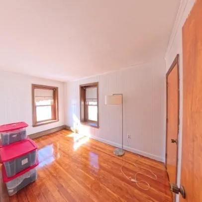 a view of an empty room with window and wooden floor