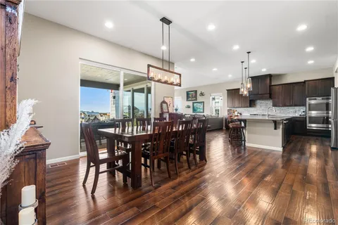 a open kitchen with stainless steel appliances granite countertop a stove a refrigerator a kitchen island a dining table and chairs with wooden floor