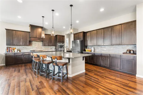 a kitchen with stainless steel appliances granite countertop a table chairs sink and cabinets