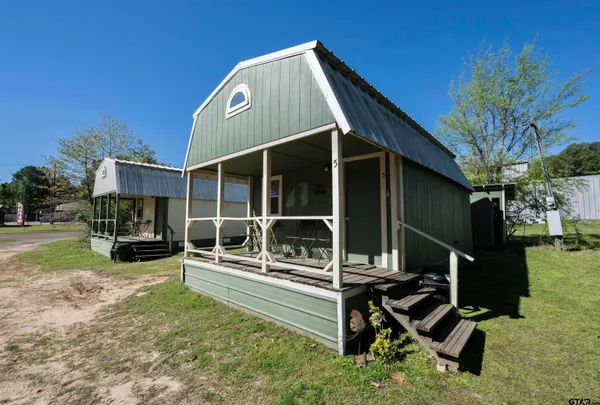 a view of a house with a yard porch and wooden fence