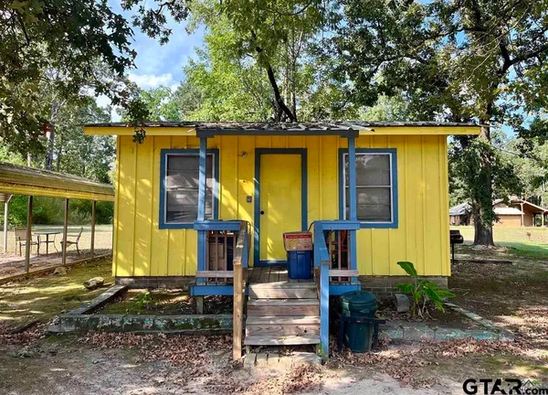 a view of a house with large trees and a car parked