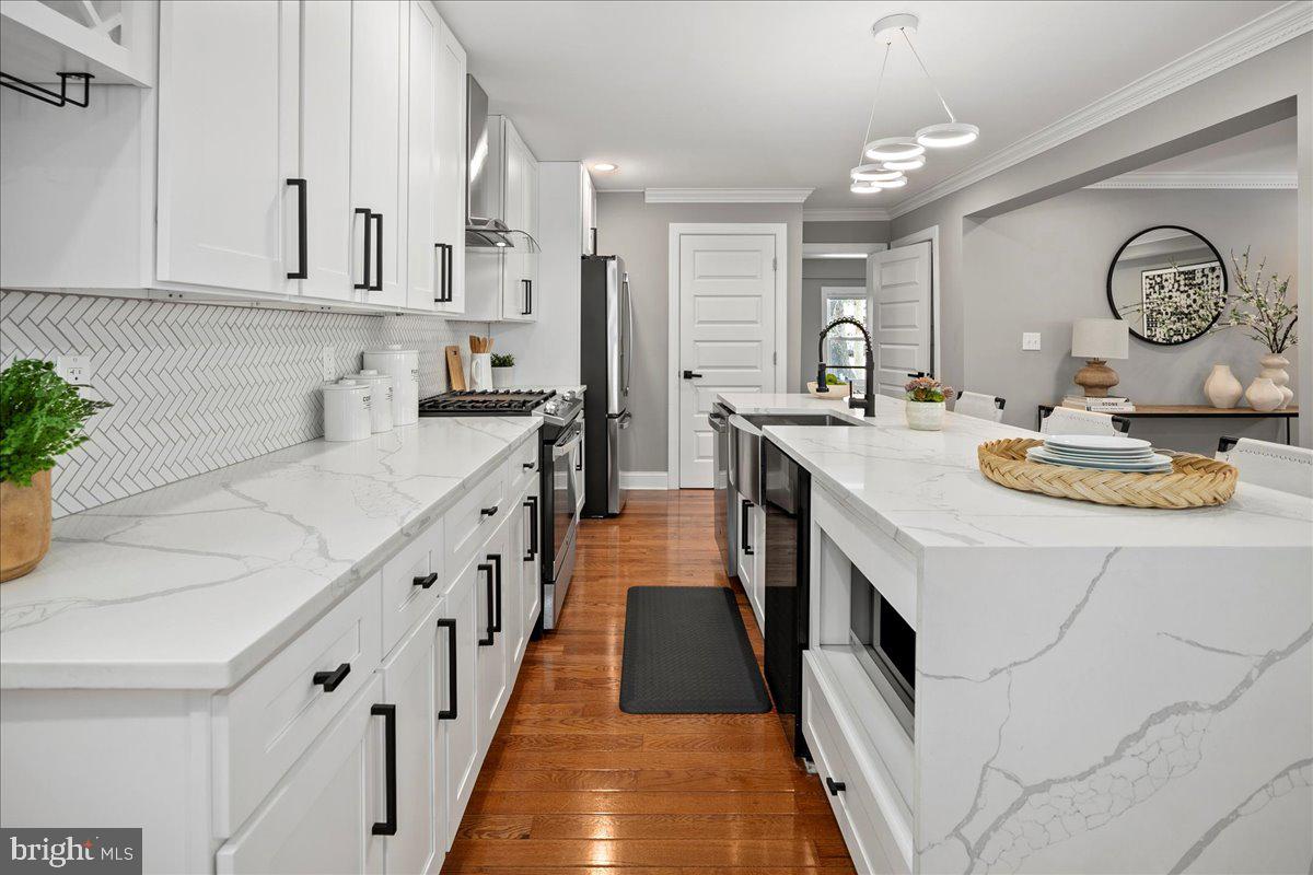 111 Sunnyside Road Silver Spring, MD 20910 - Photo 15 of 44 a large white kitchen with stainless steel appliances granite countertop a stove a sink dishwasher and white countertops with wooden floor