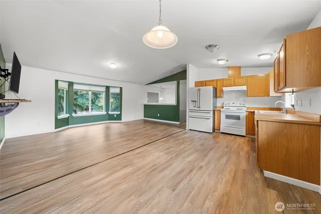 a room with stainless steel appliances wooden floors and large window