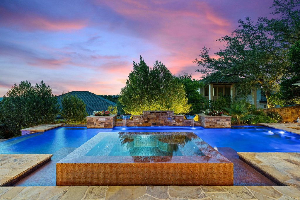 109 Largo Cove Austin, TX 78734 - Photo 30 of 40 An inviting pool and spa with waterfall features under a vibrant sunset create a private oasis.